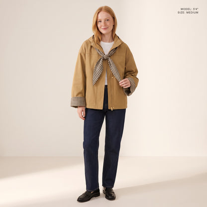 The Hartley Hooded Windbreaker in Khaki with the plaid scarf knotted at the collar, model 5 foot 4 wearing size Medium