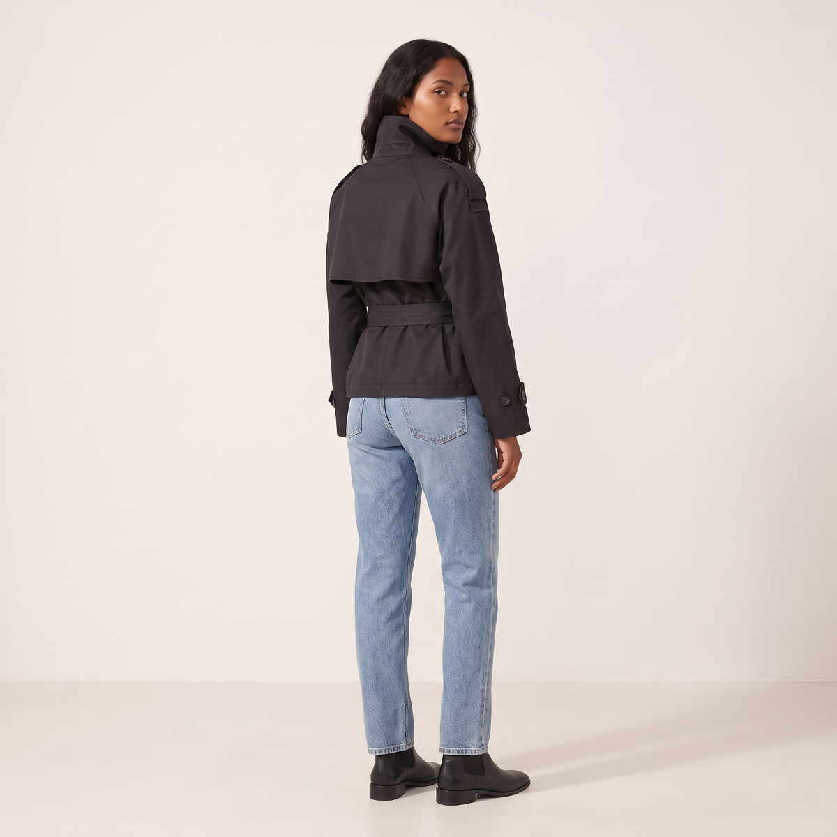 The Halston Cropped Trench in Black, back view showing the cape storm flap and belted waist